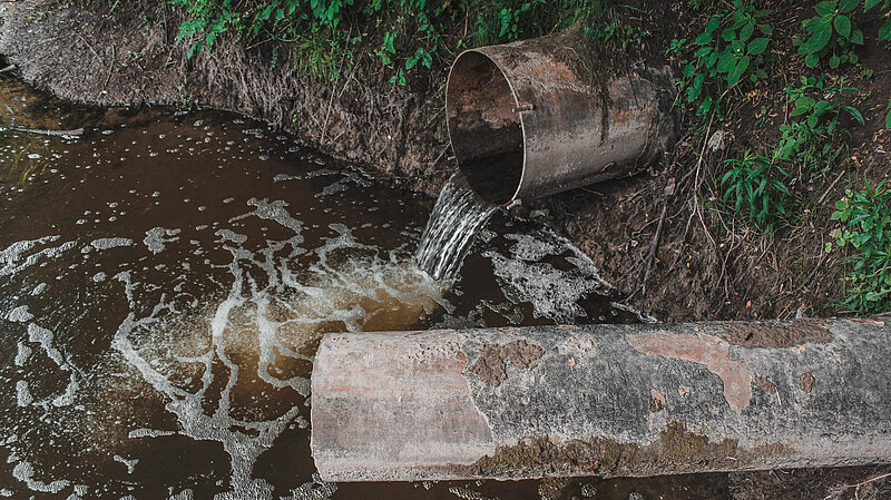 Dirty water pouring from pipe into water course